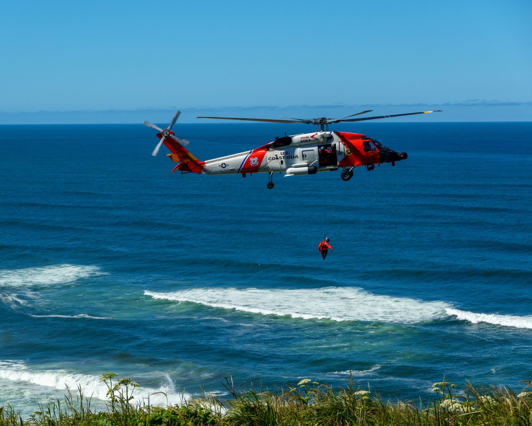 U.S. Coast Guard helicopter conducting a hoist rescue over the ocean